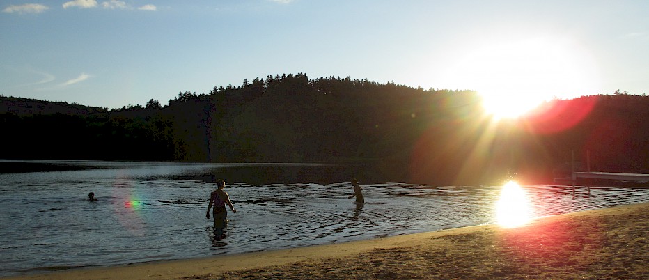 As the sun starts to dip behind the trees at Sunset Beach, campers enjoy the serenity of an evening swim.  The lifeguard was kind enough to take a few steps back for the taking of this photo.  We consider ourselves to be very spoiled on this beautiful, private little lake.